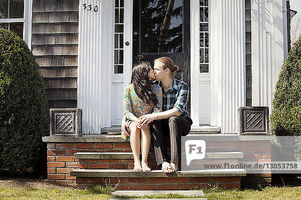 Couple kissing while on sitting steps at front stoop