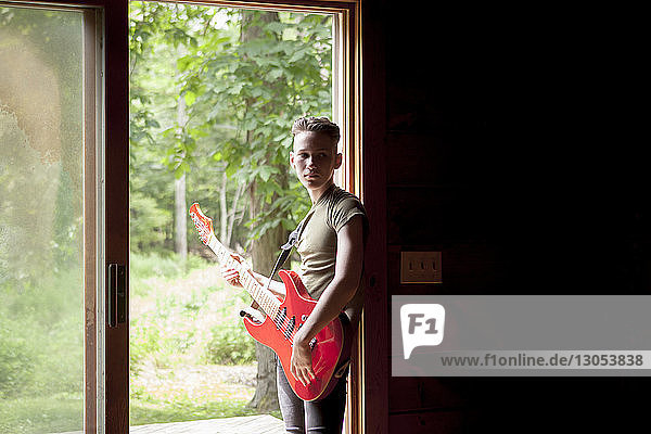 Teenager Junge spielt Gitarre  während er an der Tür steht