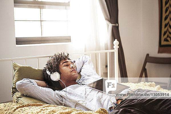 Mann hört Musik  während er sich im Bett entspannt