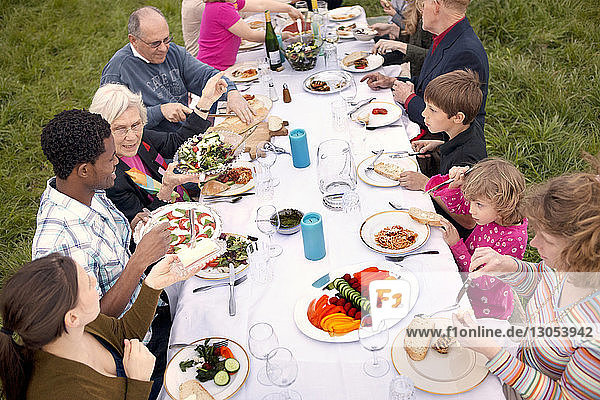 Schrägaufnahme von Familie und Freunden beim Essen am Picknicktisch