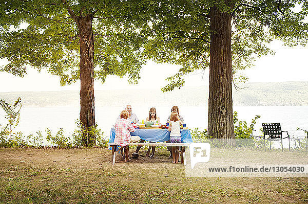 Family sitting at picnic table against Canandaigua Lake