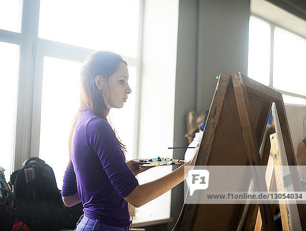 Woman painting while standing in art class