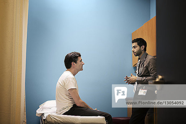 Arzt im Gespräch mit Patient auf Tablette im Krankenhaus