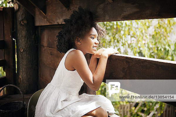 Mädchen schaut weg  während sie im Baumhaus sitzt