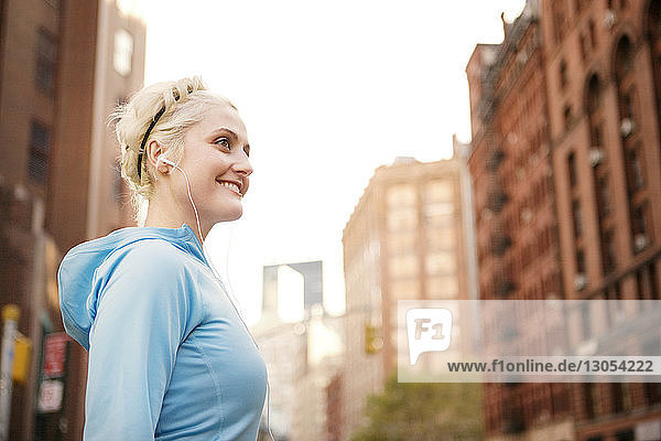 Seitenansicht einer fröhlichen Frau  die an einem sonnigen Tag vor Gebäuden steht