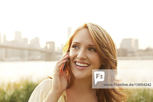 Smiling woman talking on mobile phone on sunny day