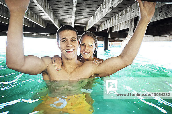 Porträt eines glücklichen Paares im See unter einem Steg