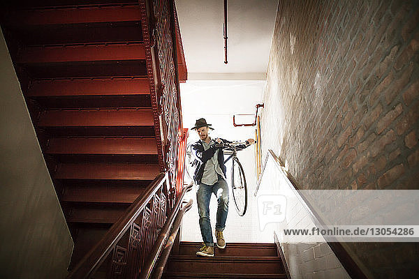 Niedrigwinkelansicht eines Mannes mit Fahrrad  der zu Hause eine Treppe hinunterfährt