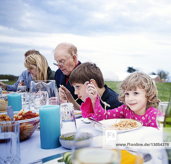Smiling girl eating food with family and friends at picnic table