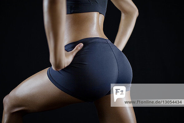 Close-up of sportswoman exercising against black background