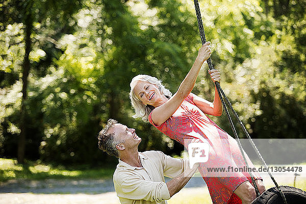Fröhliches Seniorenpaar spielt auf der Schaukel im Park