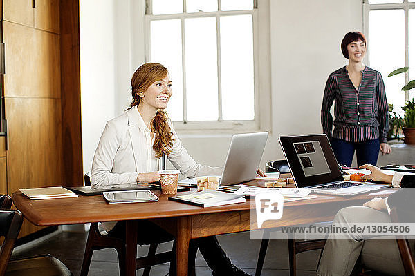 Happy businesswomen having discussion at conference table in meeting