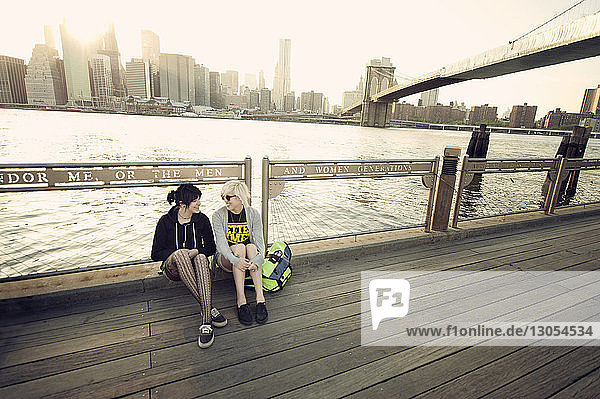 Glückliche Freunde ruhen sich auf der Promenade am East River in der Stadt aus