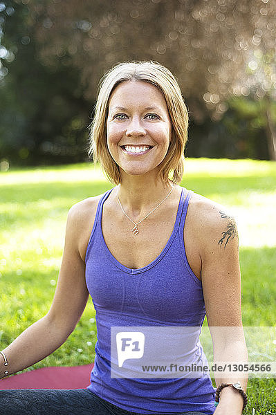 Portrait of woman exercising while sitting on field