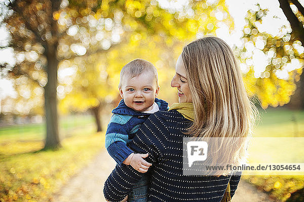 Mother carrying son while standing at park