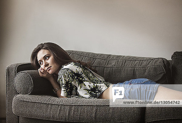 Side view of woman relaxing on sofa at home
