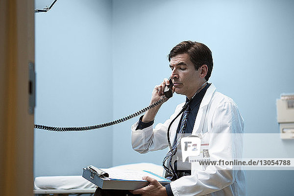 Arzt hält Telefonhörer  während er im Krankenhaus sitzt