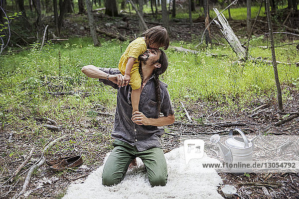 Glücklicher Vater trägt Tochter im Wald
