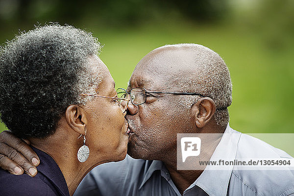 Close-up of romantic senior couple kissing in backyard