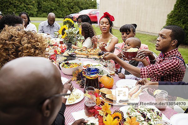 Family and friends eating food on picnic table