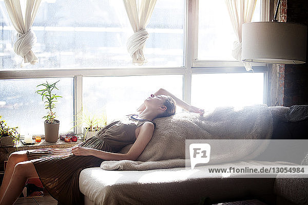 Side view of woman relaxing on sofa