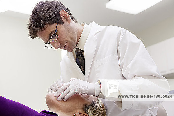 Niedrigwinkelansicht eines Zahnarztes  der den Patienten in der Klinik untersucht