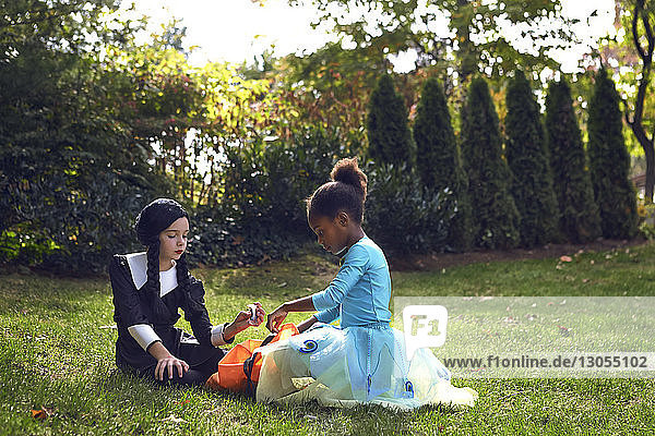 Girls in costumes sitting on field in lawn