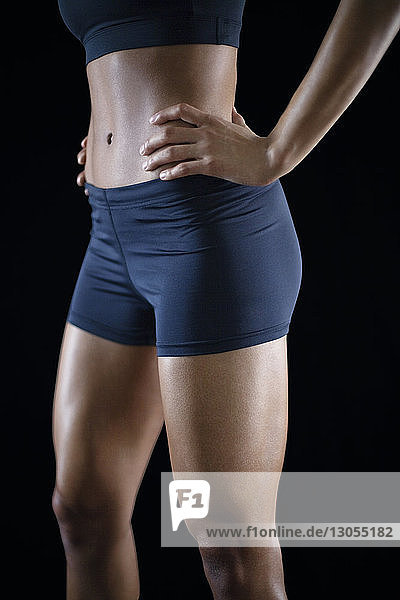 Midsection of sportswoman standing against black background