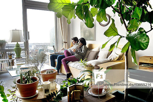 Side view of couple using technologies on sofa