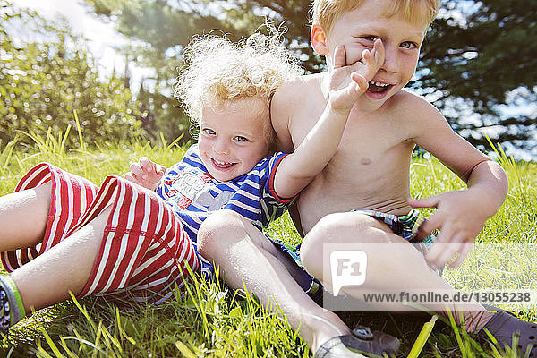 Portrait of happy siblings enjoying on grassy field