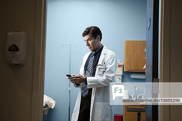 Arzt benutzt Mobiltelefon  während er im Krankenhaus steht