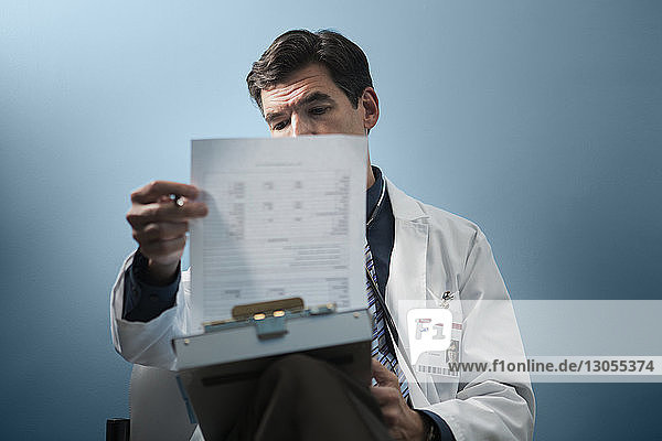 Arzt analysiert Dokumente  während er an der Wand sitzt