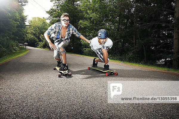 Jungen skateboarden auf der Straße inmitten von Bäumen