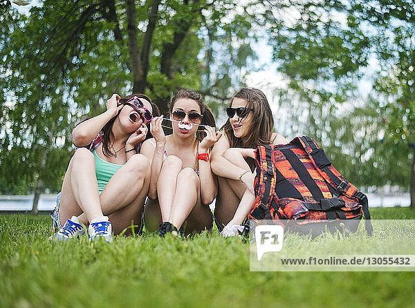 Freundinnen sitzen auf einem Grasfeld im Park