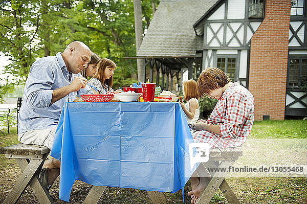 Family having food at picnic table against house
