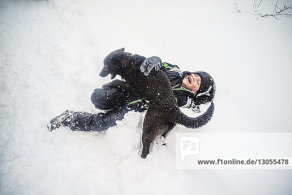 Overhead view of boy playing with dog on snow covered field