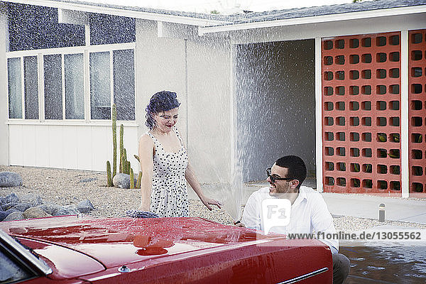 Verspieltes Paar beim Autowaschen auf dem Parkplatz