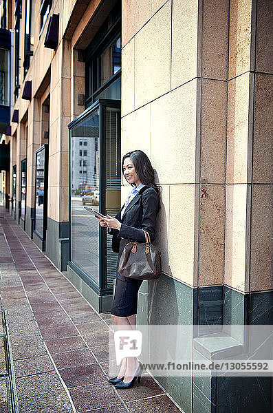 Seitenansicht einer lächelnden Geschäftsfrau  die auf einem Fußweg steht