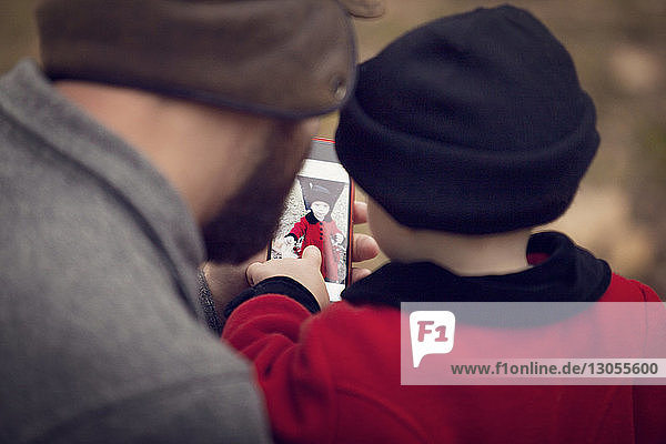 Hochwinkelansicht des Vaters und des Mädchens beim Betrachten des Fotos im Smartphone