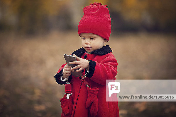 Baby benutzt Smartphone  während es im Park auf dem Feld steht