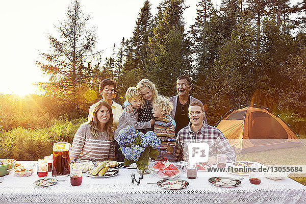 Glückliche Familie am Picknicktisch auf dem Feld