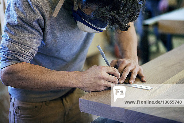 Männliche Zimmermann-Markierung auf Holzbrett in der Werkstatt
