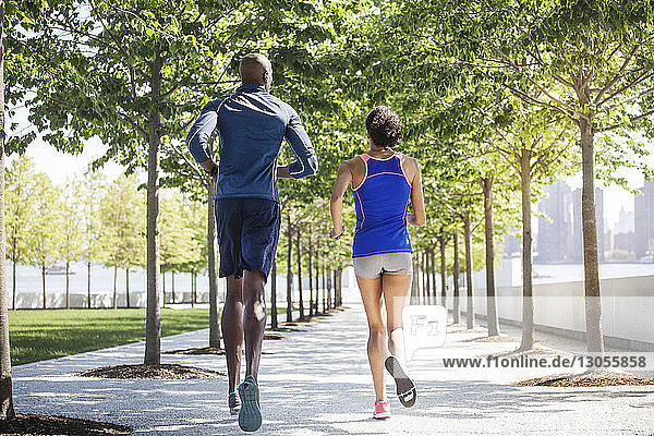 Rückansicht eines joggenden Paares auf der Promenade nach Feld