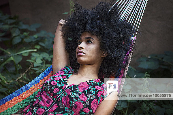 Woman with frizzy hair looking away while lying on hammock