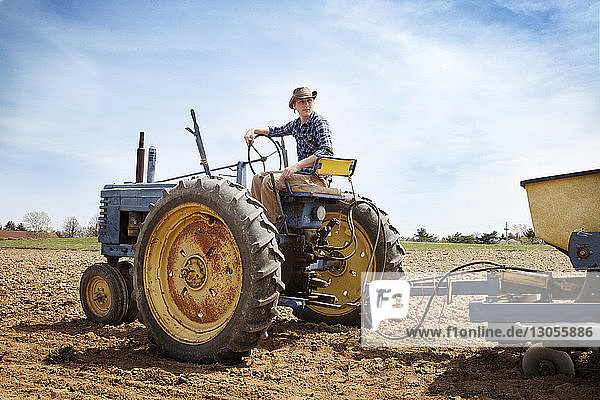 Landwirt fährt Traktor auf Feld gegen Himmel