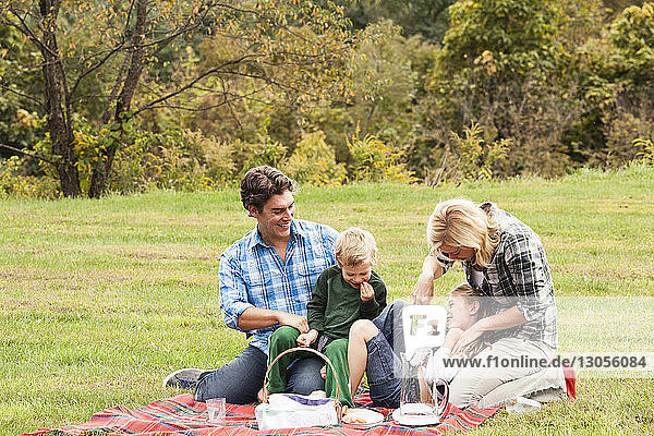 Happy family enjoying picnic on grassy field