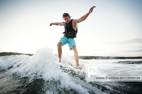 Low angle view of man wake surfing in lake against sky