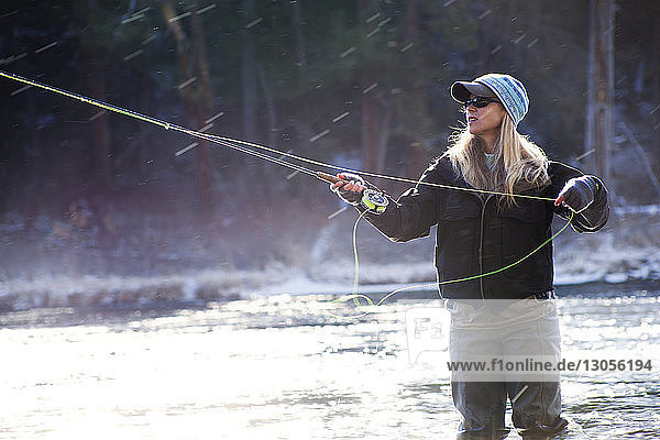 Determined woman fishing in lake on sunny day