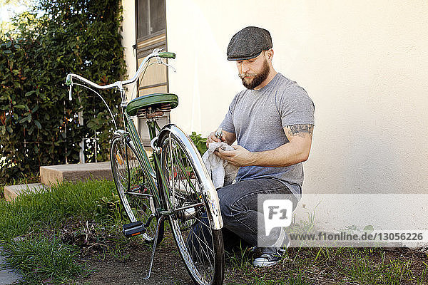 Man cleaning bicycle on field at backyard