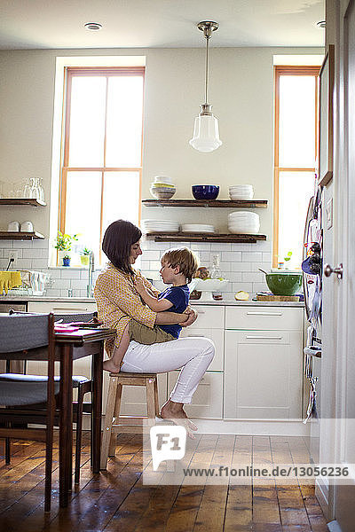 Son sitting on mother's lap in kitchen
